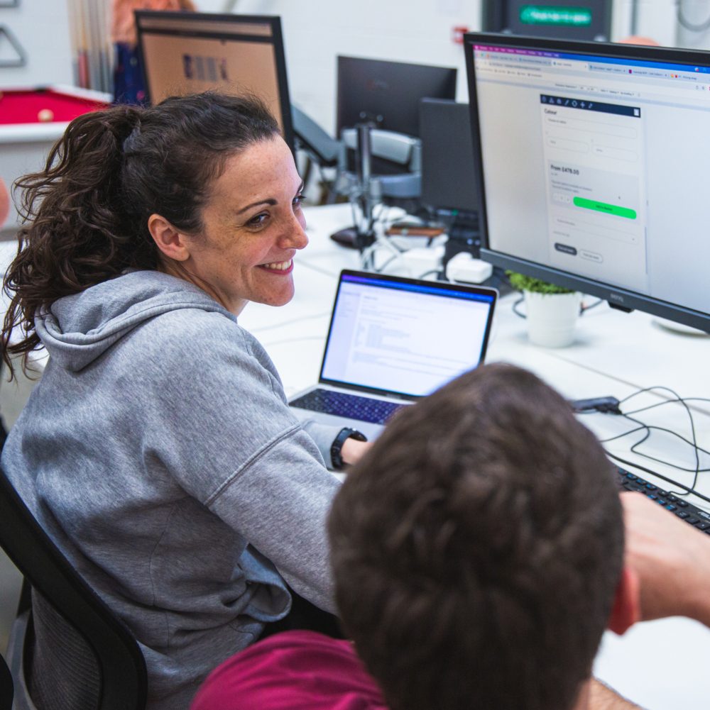 lisa smiling whilst working across two screens | ecommerce website development specialist